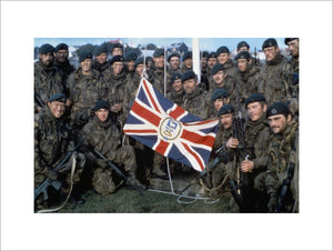 Naval Party 8901, the Royal Marine garrison of the Falkland Islands evicted by the Argentine invaders, with the Falkland Islands flag outside Government House, Port Stanley, after the Argentine surrender, June 1982.