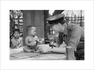 Squadron Leader Joseph Heaven, an RAF Methodist Chaplain, plays with a baby in a village near Monywa in Burma, March 1945.