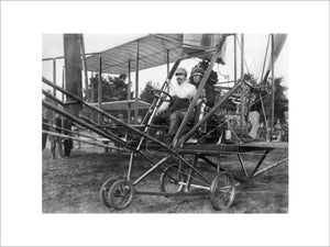 Samuel Cody at the controls of a Cody aircraft Mk II with a Native American in traditional dress as a passenger, c. 1910.