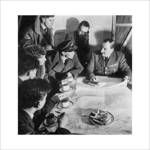 Cecil Beaton photograph of an RAF bomber crew being debriefed by the squadron intelligence officer on their return from a night raid over Germany, 1941.