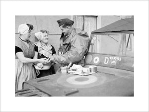 An RAF sergeant shares an alfresco lunch with two Dutch women at Nieuland, near Middelburg, soon after the town had been liberated by Allied forces, November 1944.
