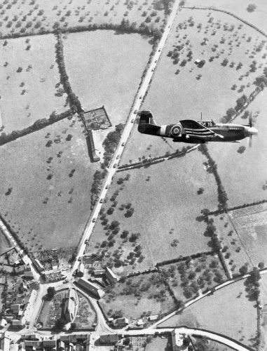 A North American Mustang  Mk I of No. 168 Squadron banking over Pierrefitte-en-Cinglais in Normandy on a tactical reconnaissance sortie, August 1944. Allied tanks can be seen on the road below.