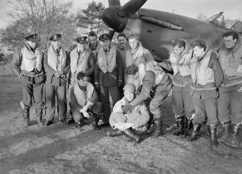 Squadron Leader Robert Stanford Tuck (centre) with pilots of No. 257 Squadron RAF under the nose of Tuck's Hawker Hurricane at Martlesham Heath. They are displaying souvenirs of their action against Italian aircraft on 11 November 1940.