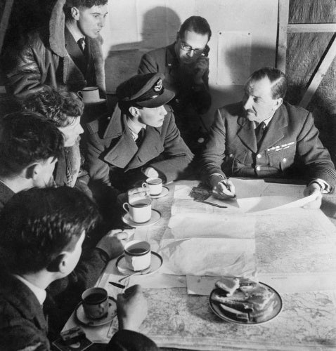 Cecil Beaton photograph of an RAF bomber crew being debriefed by the squadron intelligence officer on their return from a night raid over Germany, 1941.