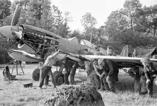 Men of an RAF Repair and Salvage Unit working on a damaged Supermarine Spitfire Mk IX of No 403 Squadron, Royal Canadian Air Force, at a forward airstrip in Normandy, 19 June 1944.