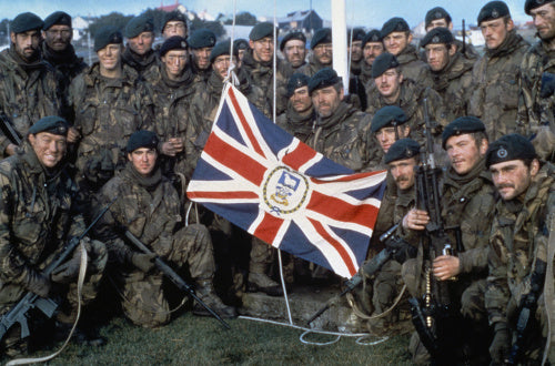 Naval Party 8901, the Royal Marine garrison of the Falkland Islands evicted by the Argentine invaders, with the Falkland Islands flag outside Government House, Port Stanley, after the Argentine surrender, June 1982.