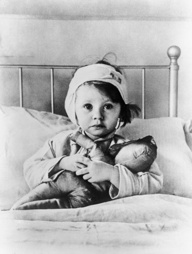 Eileen Dunne, aged three, sits in bed with her doll at Great Ormond Street Hospital for Sick Children, after being injured during an air raid on London in September 1940.