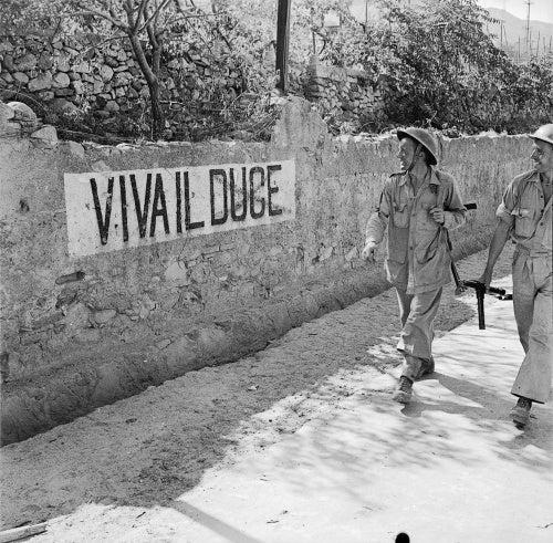 British soldiers smile at a 'Viva Il Duce' slogan on a wall in Reggio, Italy, September 1943.
