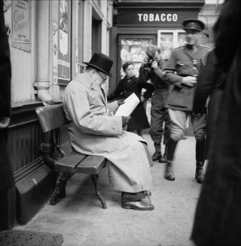 Winston Churchill reads a newspaper on the platform at St Andrews railway station, during a tour of defences and naval forces in Scotland, 23 October 1940.