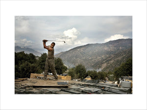 Soldier practices his golf swing at the main Korengal Outpost (KOP), Afghanistan. 2008.