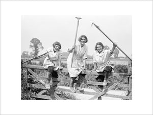 Members of the Women's Land Army climbing over a gate on a British farm during the First World War.