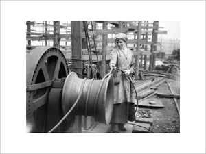 A female worker operates a winch at a shipbuilding yard on the River Clyde in Scotland during the First World War.