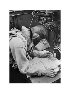 A Cecil Beaton photograph of the navigator working at his chart table in an RAF Stirling bomber, 1941.