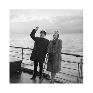 Winston Churchill gives the "V" sign in reply to cheering troops as he leaves the liner QUEEN MARY with his wife Clementine on his return from Canada, September 1943.