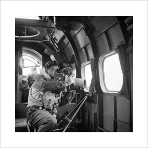 A crewman on board an RAF Coastal Command Lockheed Hudson of No. 269 Squadron, using an F.24 camera during an ice patrol from Kaldadarnes in Iceland, 5 May 1942.