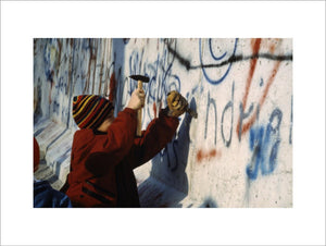 A child using a hammer and chisel to remove a piece of the Berlin Wall after its opening by the East German Government on 9 November 1989.
