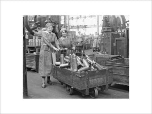 Two women munitions workers with a truck load of shell cases in the New Case Shop at the Royal Arsenal, Woolwich during the First World War.