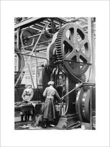 Two women munition workers operate a shell case forming machine during the First World War at the New Gun Factory of the Royal Arsenal, Woolwich, London.