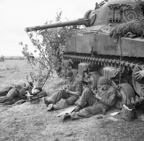 A Sherman tank crew of 'C' Squadron, 13th/18th Royal Hussars rest and write letters home by the side of their vehicle, Normandy, 10 June 1944.