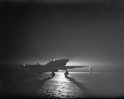 A Hawker Hurricane Mk I of No. 85 Squadron taxiing by the light of a flare at Debden, before taking off to intercept night raiders, 14 March 1941.