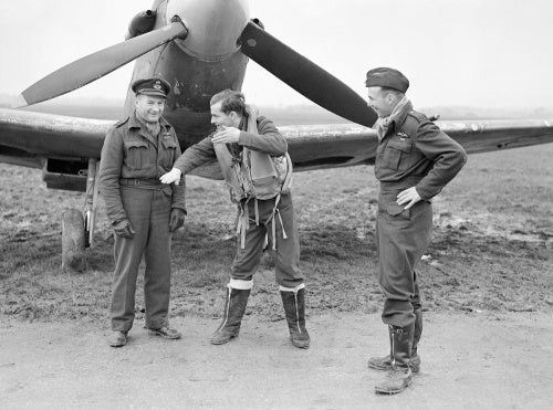 Flight Lieutenant J Pattison of No. 485 Squadron RNZAF graphically recounts a combat to Squadron Leader 'Reg' Grant (left), and Flight Lieutenant R Baker (right), in front of a Spitfire at Westhampnett, 21 January 1943.