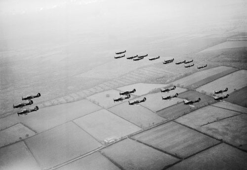 Hawker Hurricanes of No 1 Squadron, Royal Air Force, based at Wittering, Cambridgeshire, followed by a similar formation of Supermarine Spitfires of No 266 Squadron, during a flying display for aircraft factory workers, October 1940.