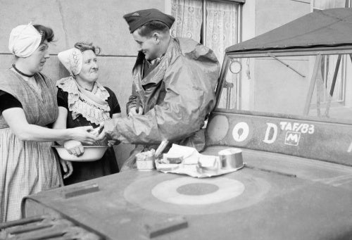 An RAF sergeant shares an alfresco lunch with two Dutch women at Nieuland, near Middelburg, soon after the town had been liberated by Allied forces, November 1944.