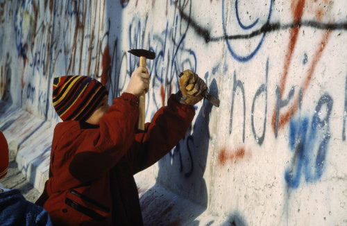 A child using a hammer and chisel to remove a piece of the Berlin Wall after its opening by the East German Government on 9 November 1989.