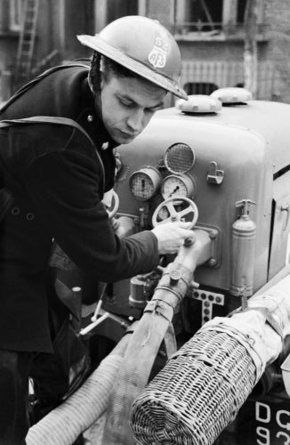 Auxiliary Fireman Norman Hepple switches on the water to the hose from a trailer pump, somewhere in London during 1940.