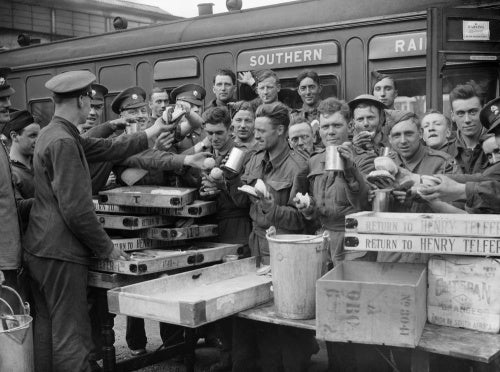 Troops evacuated from Dunkirk enjoying tea and other refreshments at Addison Road station in London, 31 May 1940.