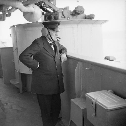 Winston Churchill wearing leather ear defenders watches gunnery practice on board HMS RENOWN whilst he was returning from Canada, September 1943.
