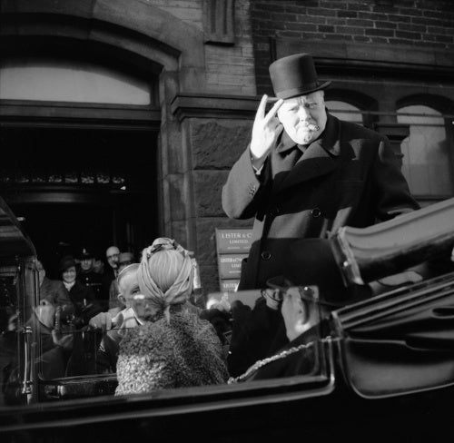 Winston Churchill, cigar in mouth, gives his famous 'V' for victory sign during a visit to Bradford, 4 December 1942.