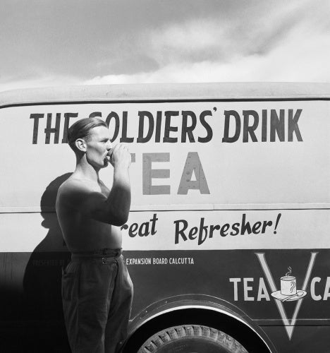 Cecil Beaton photograph of a British soldier drinking tea next to a Red Cross mobile tea wagon at Calcutta airport in 1944.