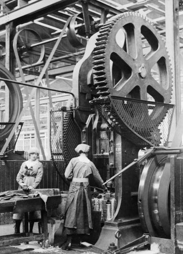 Two women munition workers operate a shell case forming machine during the First World War at the New Gun Factory of the Royal Arsenal, Woolwich, London.