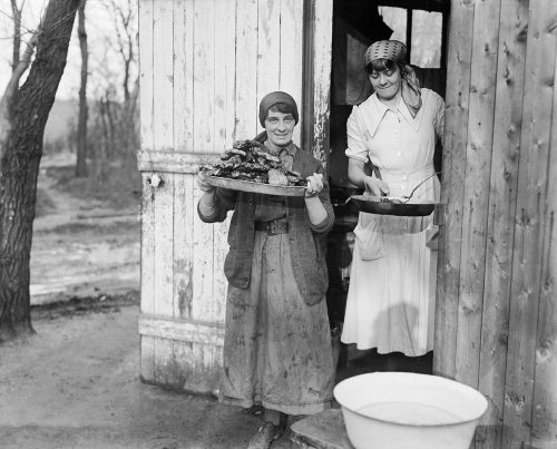 Two cooks of the First Aid Nursing Yeomanry (FANY) outside their hut with trays of food at a military hospital at Calais in January 1917.