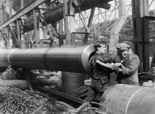 A female munitions worker is lifted into the barrel of a 15-inch naval gun manufactured at the Ordnance Works, Coventry, during the First World War, in order to clean the rifling.