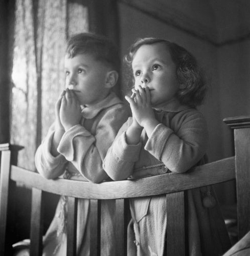 Five year old Andrew and three year old Jacqueline say their prayers before settling down to sleep at the house in which they are staying, somewhere in Surrey.