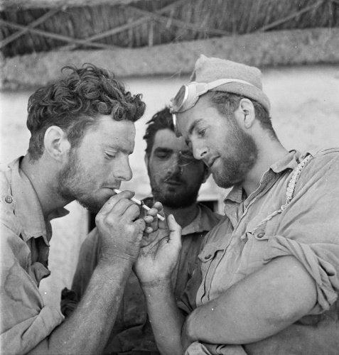 Men of the Long Range Desert Group relax with cigarettes after returning to headquarters at the end of a desert patrol, Siwa, Libya, 1942