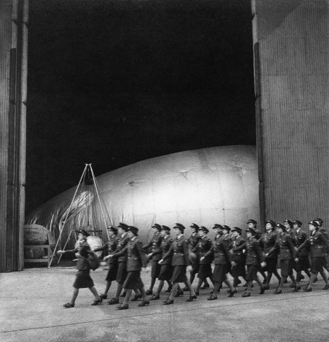 A company of WAAFs marches past a barrage balloon maintenance hangar, RAF Cardington, Bedfordshire, 1941
