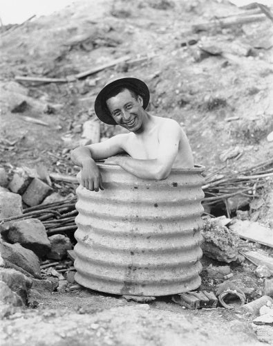 A Canadian soldier keeping cool in a home made tub in the shelling area.