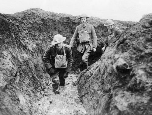 Officers of 12th Royal Irish Rifles wading through mud in a trench, Essigny, 7 February 1918.