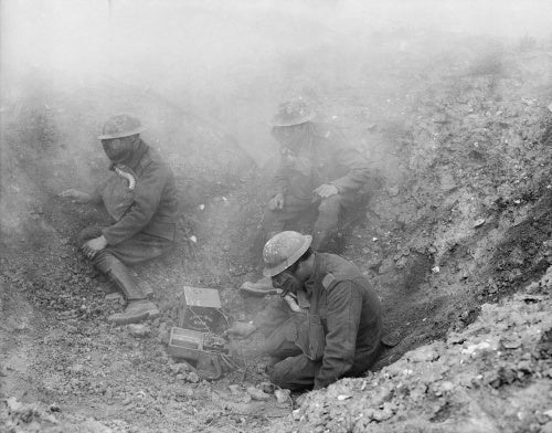 Men of the R. G. A. wearing gas masks, operating a Fullerphone in a shell hole, forward signal post.